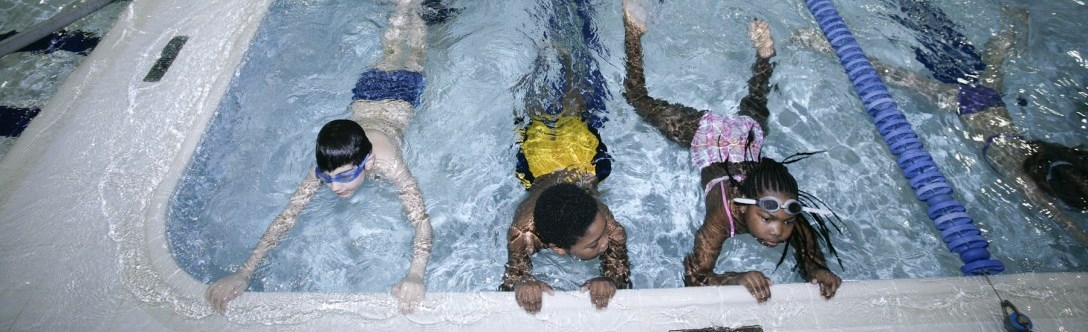 Kids holding onto edge of pool during swim lessons